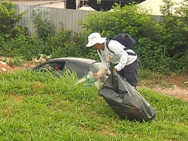 Agente de saúde limpa terreno baldio em Rio Preto para combater a dengue (Foto: Reprodução / TV Tem)