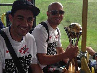 Alessandro, com a taça, posa para a foto ao lado do zagueiro Chicão no ônibus do Corinthians. Foto: Reprodução Twitter 